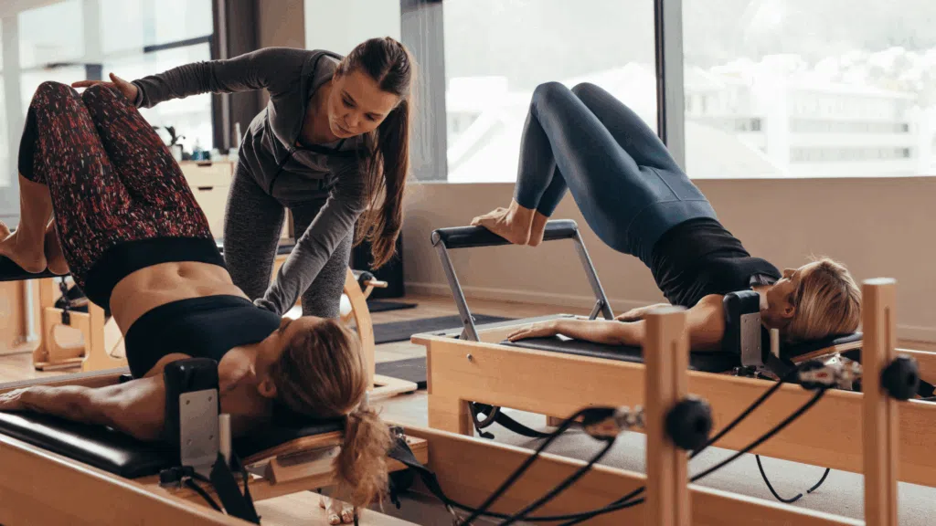 members of your journey health club being taught how to properly use a pilates reformer